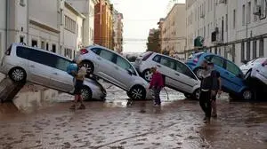 Residents walk past piled up cars following deadly floods in Sedavi, south of Valencia, eastern Spain, on October 30, 2024. Floods triggered by torrential rains in Spain's eastern Valencia region has left at least 70 people dead, rescue services said on October 30. (Photo by Manaure QUINTERO / AFP)