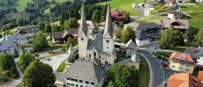 Zu sehen ist eine Luftaufnahme einer Kirche, die in einem Ortskern steht