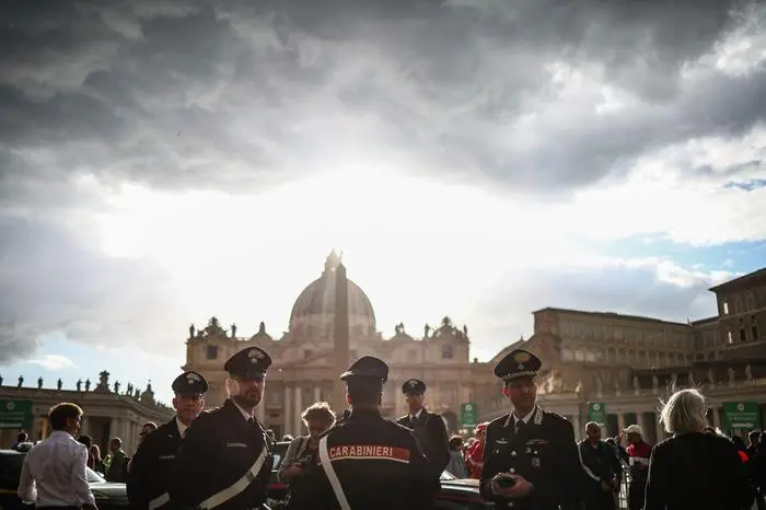 EDITORS NOTE: Graphic content / TOPSHOT - Carabineri stand guard with a background view of St Peter's Basilica of The Vatican where the late Pope lies in state, in Rome on April 24, 2025. The Vatican on April 24 said some 61,000 people had already paid their respects to Pope Francis, whose body is lying in state in St Peter's Basilica ahead of his funeral. (Photo by HENRY NICHOLLS / AFP)