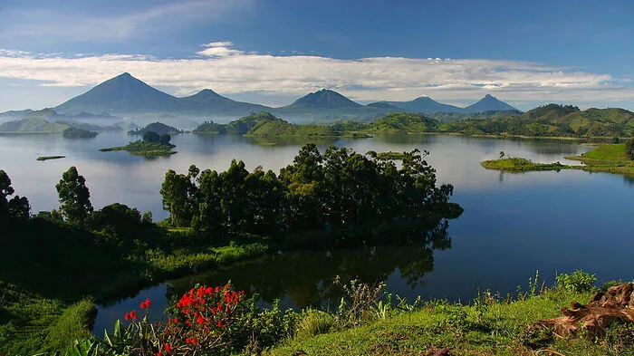 Lake Mutanda. Eine Kamera ist unbedingt erforderlich, wenn Besucher in einem traditionellen Einbaum-Kanu über den Lake Mutanda paddeln. Ihnen eröffnet sich ein wunderschönes Panorama: Im Hintergrund spiegeln sich auf dem glatten Wasser die Gipfel der acht Virunga-Vulkane.