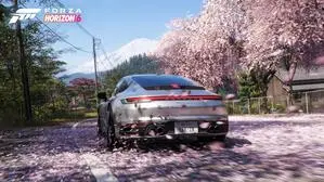 Ein Porsche fährt auf einer Straße, die mit rosa Kirschblüten bedeckt ist. In der Ferne sieht man den Berg Fuji