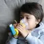 Poor boy tired from chest coughing holding inhaler mask, Child closing his eyes while using the volumtic for breathing treatment,Tried Kid having asthma allergy using the asthma inhaler