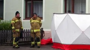 Zwei Feuerwehrleute schirmen einen Tatort ab | Einsatzkräfte schirmen  am 16. September des Vorjahres den Tatort ab