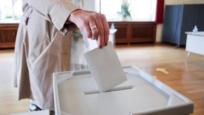Eine Frau wirft ein Kuvert in die Wahlurne