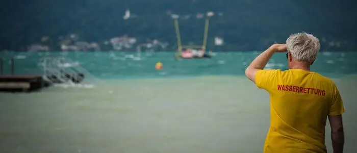 Man sieht einen Wasserretter, der auf den See hinausblickt