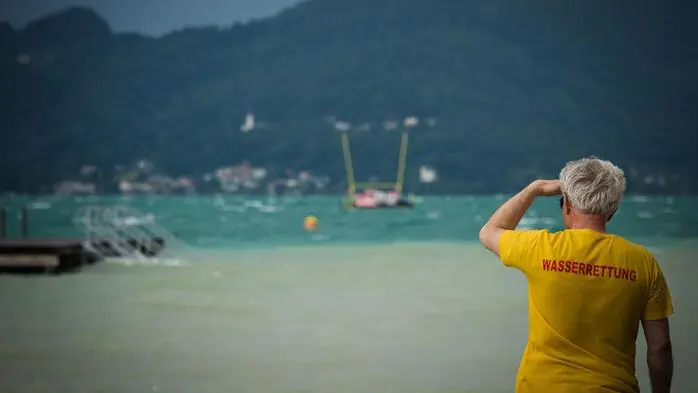 Man sieht einen Wasserretter, der auf den See hinausblickt