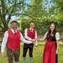Zwei Männer und eine Frau, alle in Tracht, lächeln in die Kamera.