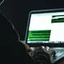 Ein mit Kapuzenpullover gekleideter Mann vor einem Laptop | In betrügerischer Absicht wurden täuschend echt wirkende E-Mails verschickt