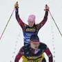 Carina Edlinger, of Austria, behind her guide Jakob Mainz, celebrates crossing the finish line to win the gold medal in the para cross-country women's sprint, classic VI, at the Nordic World Ski Championships in Trondheim, Norway, Wednesday, March 5, 2025. (AP Photo/Matthias Schrader)