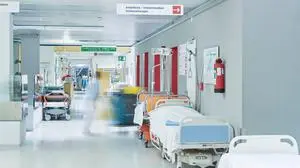 Flur im Krankenhaus mit unscharfem Arzt in Bewegung und Lift rot mit Bett