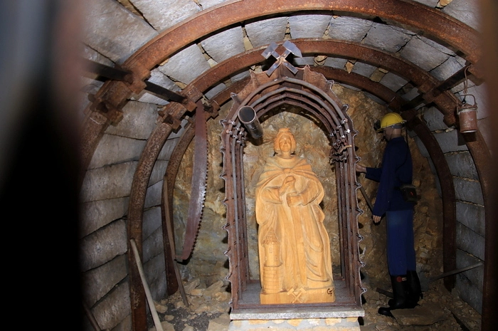 Zur Bergbauerinnerungsstätte gehört auch eine Statue der Schutzpatronin der Bergleute, der hl. Barbara, die in einem „Mundloch“, einem Stolleneingang, steht.