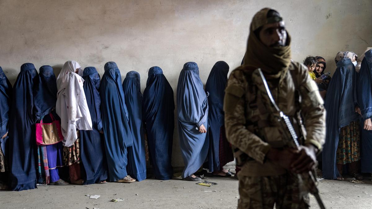 Alltag in Afghanistan: Ein Taliban bewacht Frauen, die auf Essensrationen warten