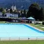 Ein Becken in einem Freibad. Dahinter die Ortschaft Gurk mit dem Gurker Dom 