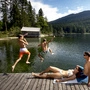 Zwei Kinder springen von einem Steg in den See