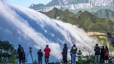 Schaulustige bestaunen den Wolkenwasserfall über dem Berg Jinfoshan in China | Wolkenwasserfall in China