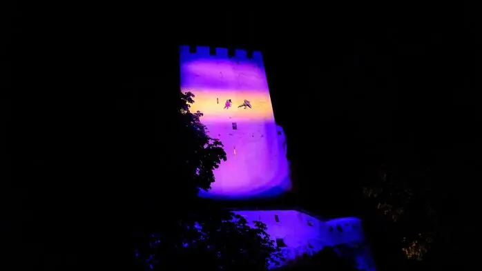 Zwei Artisten schweben an einer erleuchteten Mauer von Schloss Bruck hinab