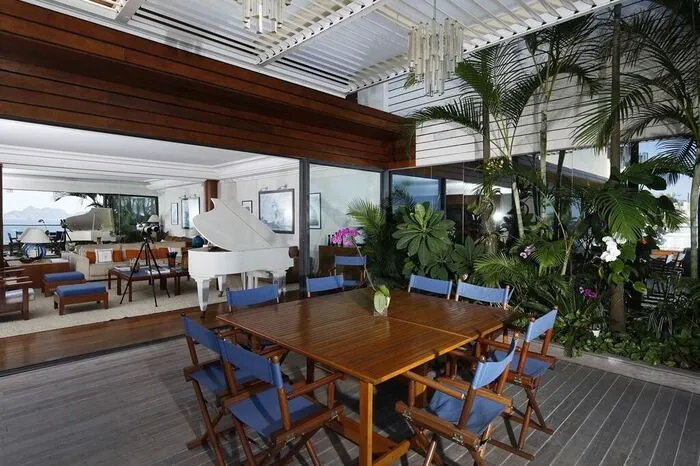 ...Das Wohnzimmer öffnet sich zur Terrasse hin, auf der sich ein Garten mit Palmen und exotischen Pflanzen befindet...  