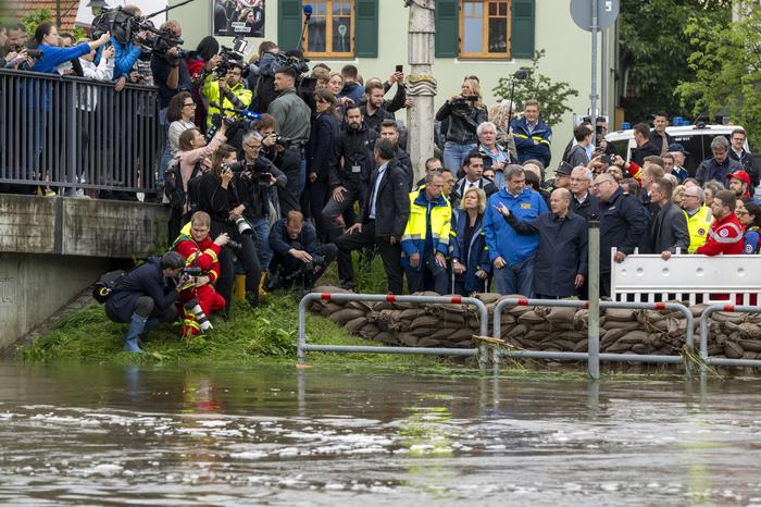 Bundeskanzler Olaf Scholz, Bayerns Ministerpräsident Markus Söder, Bundesinnenministerin Nancy Faeser stehen hinter einer Absperrung aus gefüllten Sandsäcken bei einer Ortsbesichtigung im vom Hochwasser betroffenen oberbayerischen Reichertshofen.