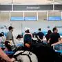 Travelers wait in line at an American Airlines counter at Ronald Reagan Washington National Airport in Arlington, Virginia, on July 2, 2022. - US airlines are bracing customers for what will probably be a bumpy Fourth of July holiday weekend as the industry struggles to manage a surge in travel demand that probably exceeds its current capacity. Flight delays and cancellations created a difficult start for many travelers leaving town for the holiday. (Photo by Stefani Reynolds / AFP)