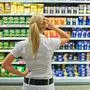 Eine Frau ist mit der großen Auswahl in einem Supermarkt beim Einkauf überfordert.