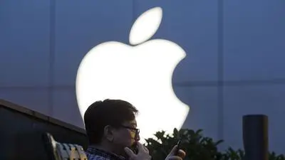 FILE - In this Friday, May 13, 2016, file photo, a man uses his mobile phone near an Apple store in Beijing. On Wednesday, July 12, 2017, Apple announced it will open a data center in mainland China with ties to the country’s government, raising concerns about the security of iCloud accounts that store personal information transferred from iPhones, iPads and Mac computers there. (AP Photo/Ng Han Guan, File)