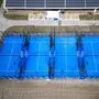 Vier blaue Padeltennisplätze nebeneinander.