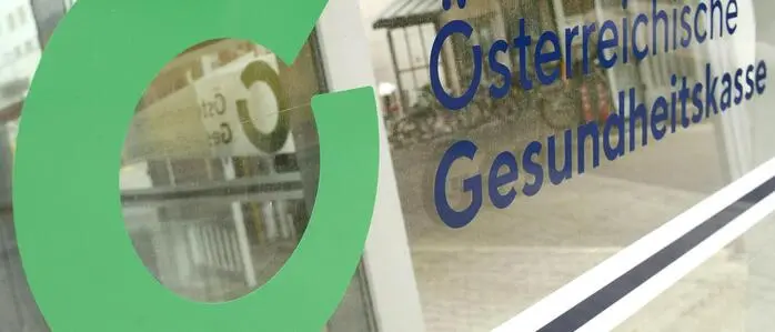 Das Bild zeigt das Logo der Österreichischen Gesundheitskasse auf einer Fensterscheibe