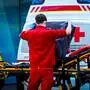 Ein Sanitäter steht hinter einem Rettungswagen