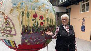 Künstlerin Hannelore Fasser im Brucker Rathaushof mit einer der drei Bälle ihrer Ausstellung, der für die Erde steht