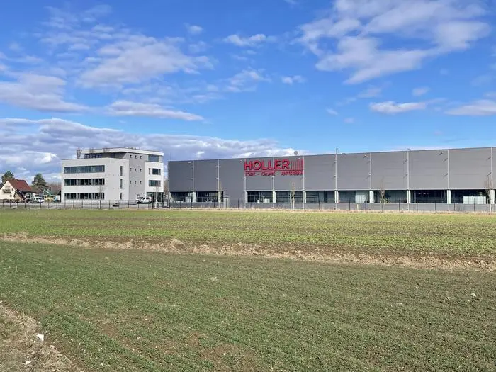 Die neue Werkshalle ist mit 210 Metern Länge von weitem sichtbar. Dahinter zu sehen: das neue vierstöckige Bürogebäude