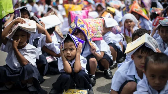 Erdbebentest in der philippinischen Hauptstadt: Im großen Stil wurde in zahlreichen Schulen Manilas der Ernstfall geprobt. Schulhefte bieten Schutz vor imaginären Gegenständen.