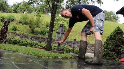 Michael Liegl zeigt, wie hoch das Wasser im Garten des Gasthofes der Familie stand