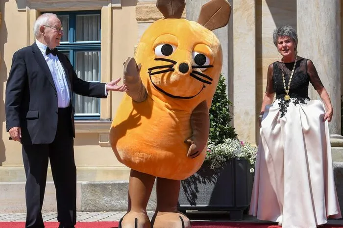 Gedreht wird ein Beitrag darüber, wie eine Aufführung der Bayreuther Festspiele funktioniert. Die Maus kam in Begleitung von Armin Maiwald, langjähriger Sprecher der Sendung, zur Premiere.