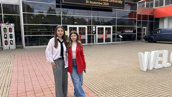 Zwei junge Frauen stehen vor einem Fachhochschulgebäude