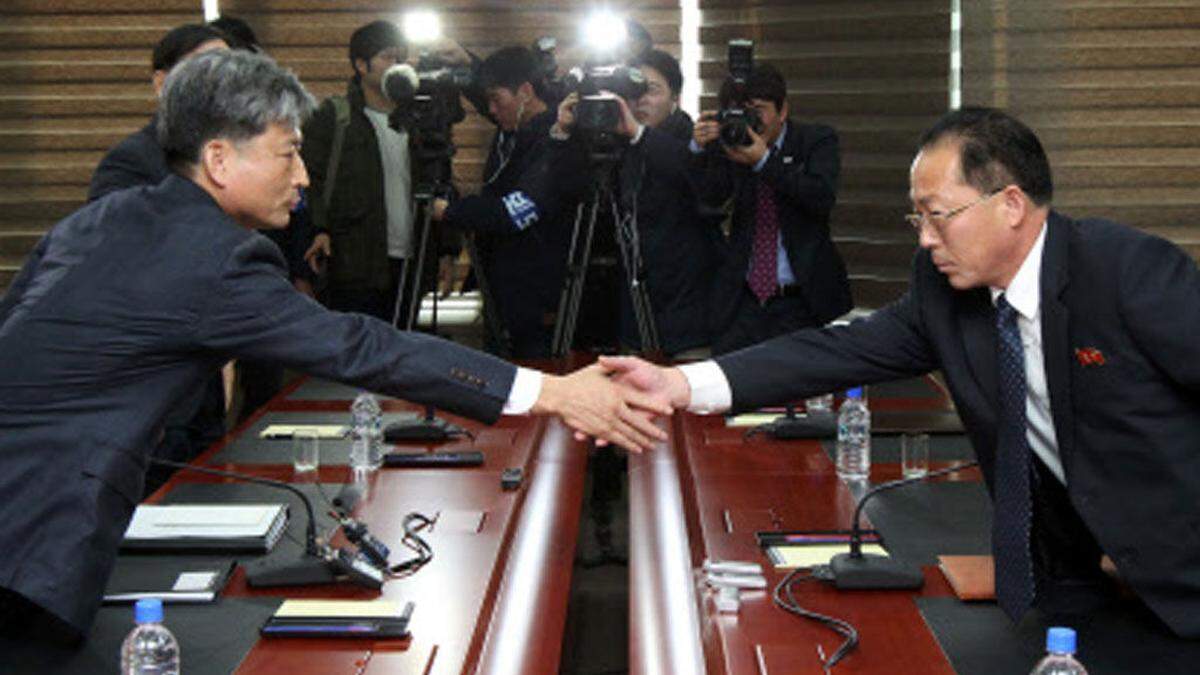 Ernste Gesichter beim Händeschütteln zwischen Vertretern von Süd- und Nordkorea