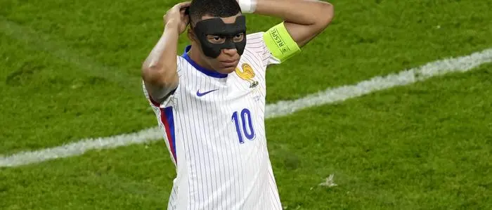 Kylian Mbappe of France puts on a protective mask during a quarter final match between Portugal and France at the Euro 2024 soccer tournament in Hamburg, Germany, Friday, July 5, 2024. (AP Photo/Darko Vojinovic)