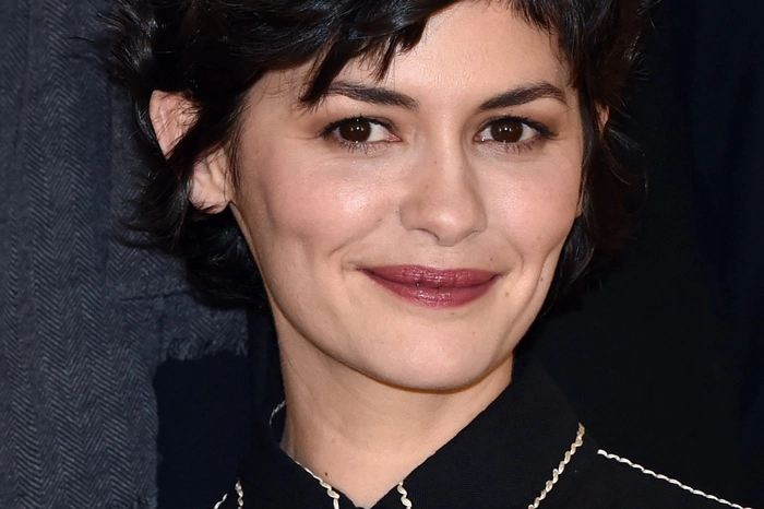 Einfache Kniffe, große Wirkung. Krempeln Sie die Ärmel Ihrer weißen Bluse grob über den Pullover. Das verleiht dem Outfit ohne Aufwand eine lässige Note. Im Bild: Audrey Tautou