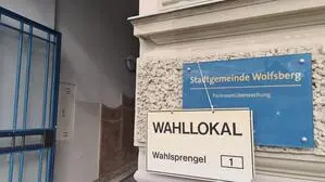 Schild „Wahllokal“ hängt an Hausschild „Stadtgemeinde Wolfsberg“