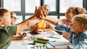 Happy teacher and joyful school kids celebrate together  successful completion of collective school work in a light classroom