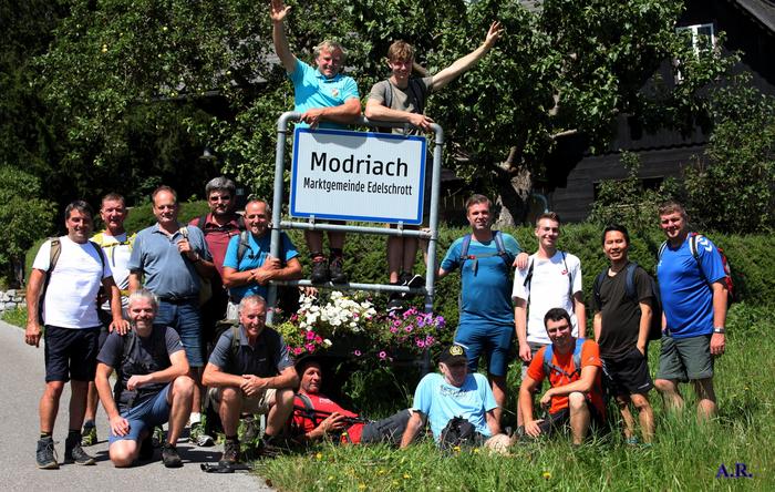 Die gutgelaunte Pilgergruppe an der Ortstafel von Modriach