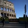 A woman wearing a protective mask waits at a bus stop near the Colosseum monument along a deserted Via dei Fori Imperiali on March 23, 2020 in Rome, during the country's lockdown aimed at stopping the spread of the COVID-19 (new coronavirus) pandemic. (Photo by Filippo MONTEFORTE / AFP)