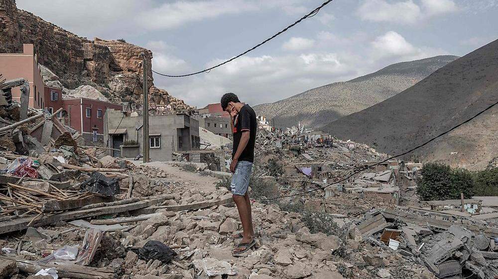 Ein junger Mann steht auf den Trümmern eines Hauses.