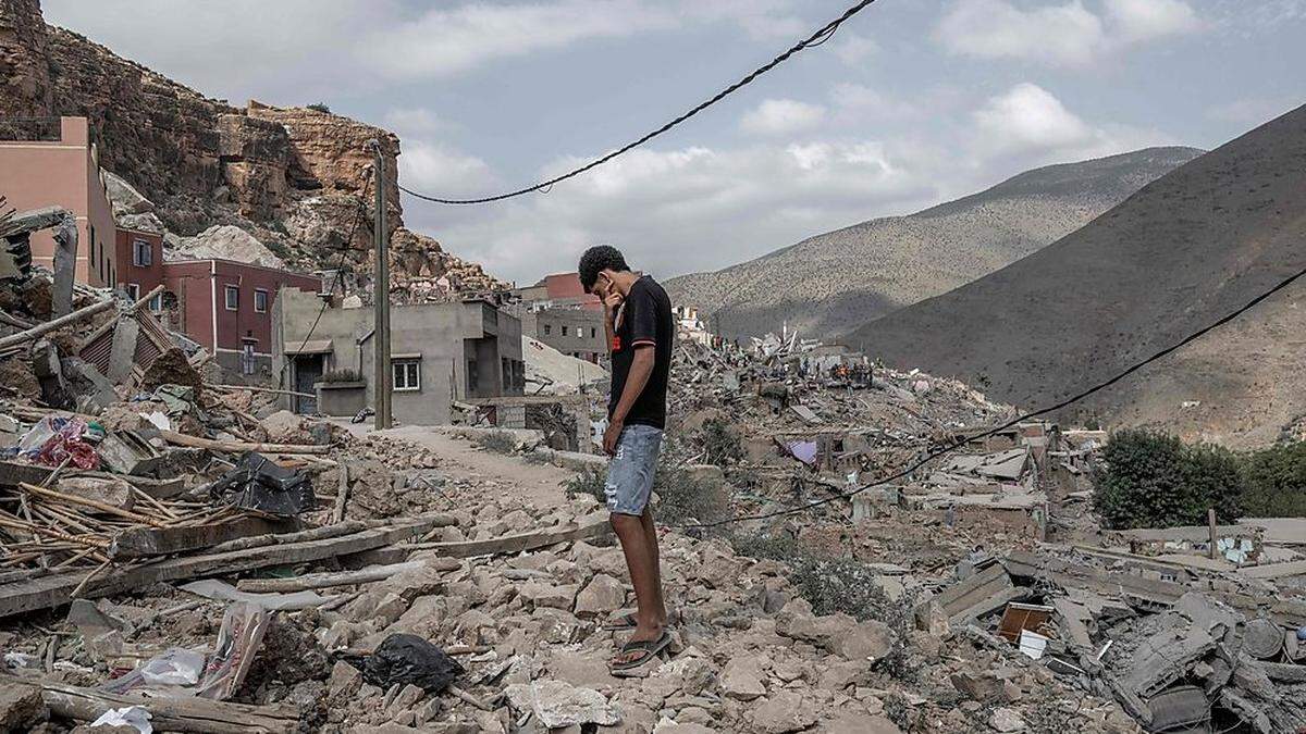 Ein junger Mann steht auf den Trümmern eines Hauses.