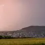 Man sieht Gewitterwolken über einer Landschaft, gerade fährt ein Blitz vom Himmel