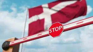 Closed boom gate on the Danish flag background. Restricted entry or certain ban in Denmark. 3D rendering, Closed boom gate on the flag background. Restricted entry or certain ban 3D
