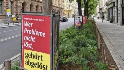 Plakate von ÖVP, Neos, SPÖ und weiter hinten FPÖ und KPÖ stehen in der Neutorgasse in Blumenbeeten - dort dürfen sie aber nicht stehen