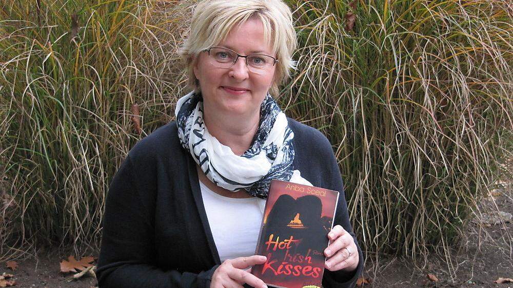 Anba Sceal hält ihren Debütroman „Hot Irish Kisses“ stolz in Händen 	