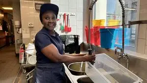 Eine Frau mit Kappe und blauem Shirt steht an einer Abwasch