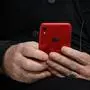 Irish rock band U2 singer Bono's hands hold is "Red" iphone during a session pannel at the World Economic Forum (WEF) annual meeting, on January 23, 2019 in Davos, eastern Switzerland. (Photo by Fabrice COFFRINI / AFP)