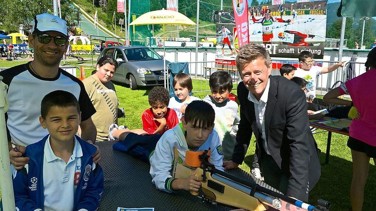 Michel Wenzel, Biathlon-Trainer beim Askö Villach (links), Landessportdirektor Arno Arthofer und die Jugendlichen beim Biathlon-Stand